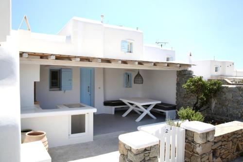 a white house with a table on a patio at Villa ANASA private Pool & Jacuzzi 8pax at Panormos in Panormos Mykonos