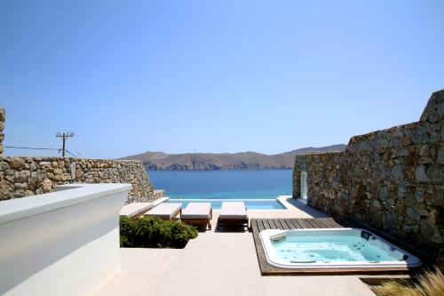 a hot tub on a patio with a view of the water at Villa ANASA private Pool & Jacuzzi 8pax at Panormos in Panormos Mykonos