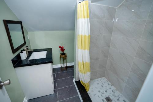 een badkamer met een douche met een geel en wit douchegordijn bij Cute 2-story, 2-bdrm Loft, Mins to Beach and Lake in Cobourg