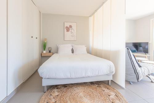 - une chambre blanche avec un lit et un tapis dans l'établissement Le Pin Parasol à Cassis - Studio 3 personnes by K6, à Cassis