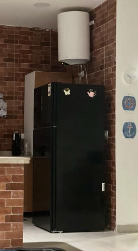 a black refrigerator in a kitchen next to a brick wall at Villa Amoun-4 Rooms now in Sidi Krir 