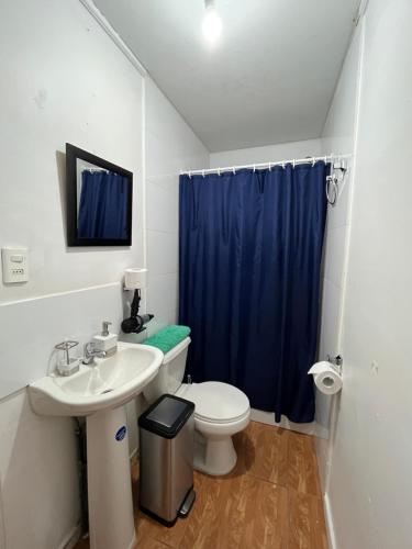 a bathroom with a toilet and a blue shower curtain at Cabañas Caur in San Pedro de Atacama