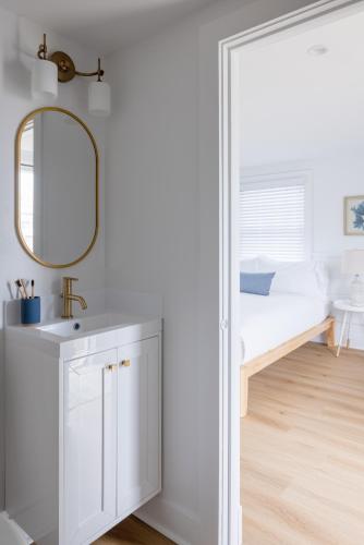 a bathroom with a mirror and a sink and a bed at Inn on the Beach in Harwich Port