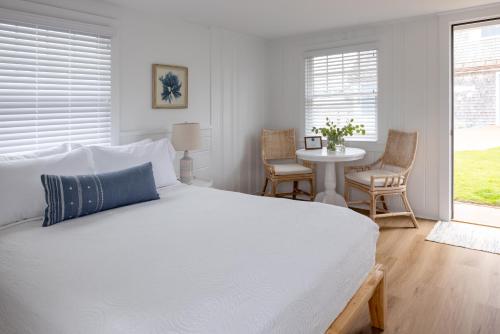 a bedroom with a white bed and a table and chairs at Inn on the Beach in Harwich Port