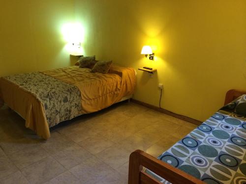 a bedroom with two beds and two lamps on the wall at Ciudad de las Colinas in Victoria