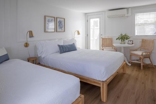 a bedroom with two beds and a table with a chair at Inn on the Beach in Harwich Port