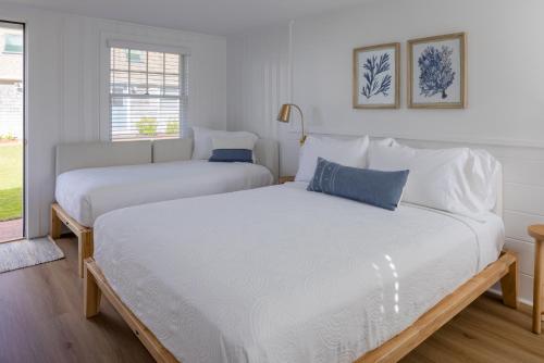 two beds in a white room with a window at Inn on the Beach in Harwich Port