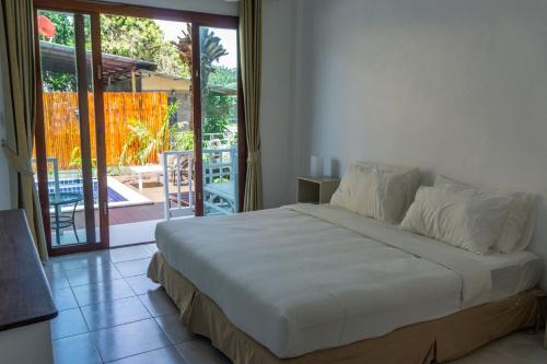 a bedroom with a bed and a sliding glass door at Isla Tortuga Diving & Hostel in Koh Tao