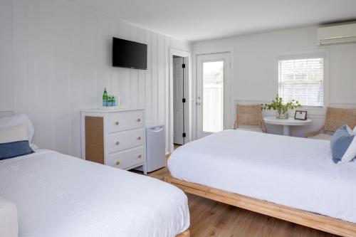 a white bedroom with two beds and a desk at Inn on the Beach in Harwich Port