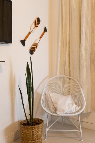 a white chair and a plant next to a window at Casa azul Ilha Grande in Abraão