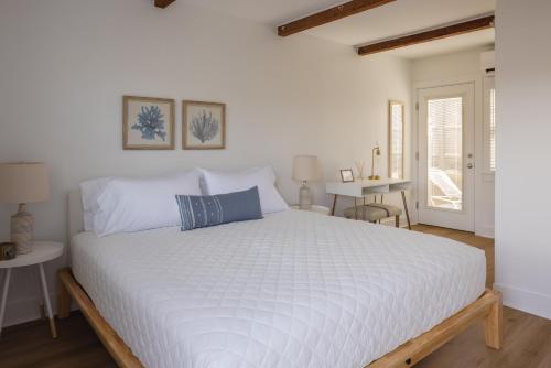 a bedroom with a white bed with a blue pillow at Inn on the Beach in Harwich Port