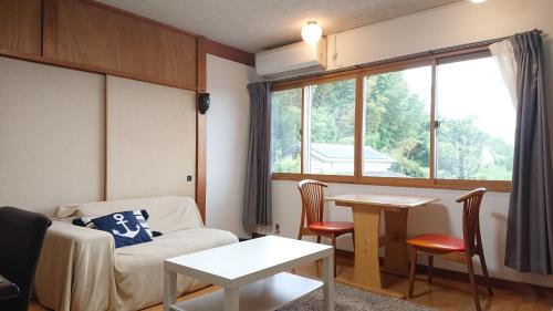 a living room with a couch and a table and a window at Niwamori_org in Nara