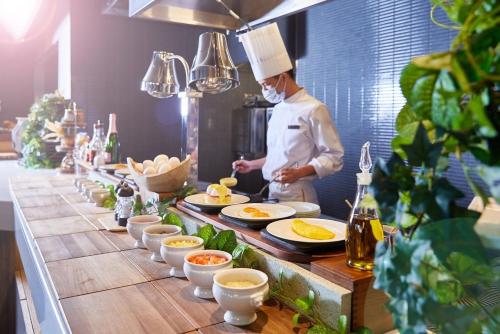 a chef standing in a kitchen preparing food at Hotel Collective in Naha