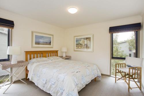 a bedroom with a bed and a desk and two windows at Purfect Purnell in Anglesea