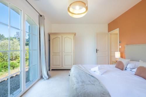 une chambre avec un lit et une grande fenêtre dans l'établissement SERRENDY  BIJOU de 280m2 au calme absolu avec piscine à débordement , à Roquefort-les-Pins