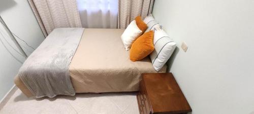 a bed with orange and white pillows and a wooden table at Hermoso Apartamento Ubicado en Zona Céntrica de Medellín in Medellín