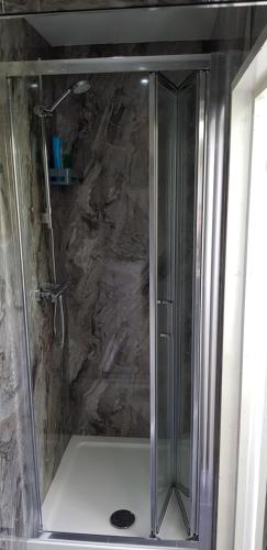 een douche met een glazen deur in de badkamer bij U-DIN HOMES in Weymouth