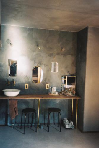 a bathroom with a counter with a sink and two mirrors at ゲストハウスよるよなか in Nagoya