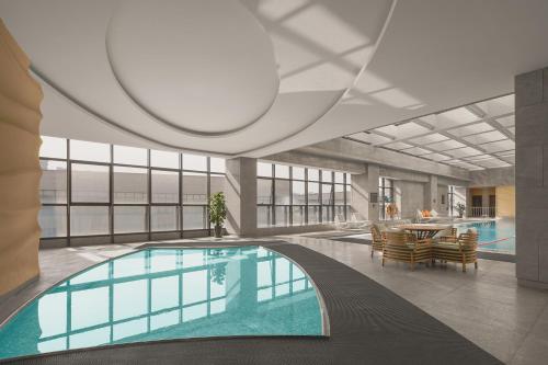 a pool in a building with a table and chairs at Gran Melia Xi'an in Xi'an