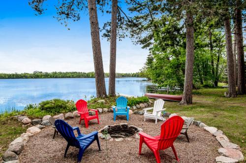 a group of chairs around a fire pit by the water at Whispering Pines in Harshaw
