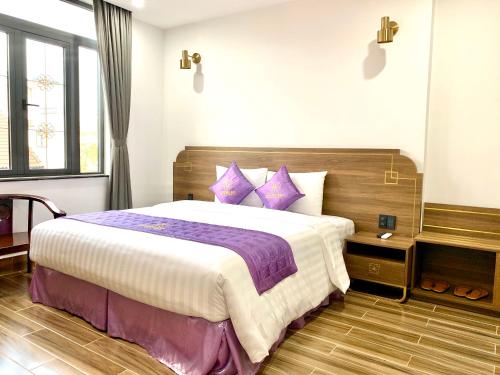 a bedroom with a large bed with purple pillows at Golden Inn Hotel in Hue