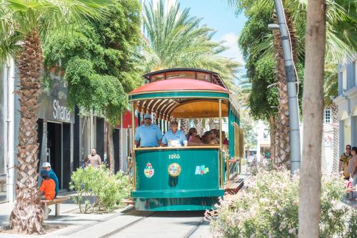 a green trolley with people riding on it at Victoria City Hotel in Oranjestad