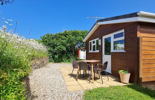 a small shed with a table and chairs next to it at Little Oaks Chalet - St. Merryn, Padstow in Padstow