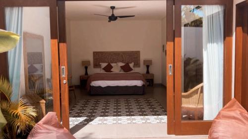 a bedroom with a bed and a door leading into a room at The Seaglass Villas Bingin in Uluwatu