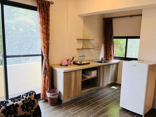 a kitchen with a white refrigerator in a room with windows at 溪頭18號 in Lugu