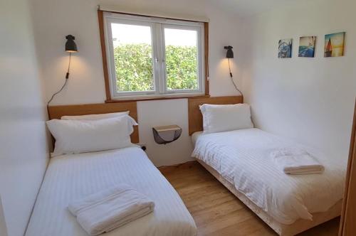 2 camas en una habitación pequeña con ventana en Little Oaks Chalet - St. Merryn, Padstow, en Padstow