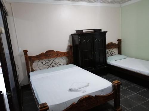 two beds sitting in a room with white sheets at Hotel el Tucan Alajuela in Alajuela City