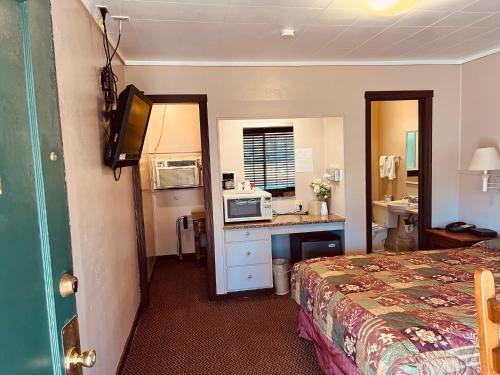a hotel room with a bed and a desk with a microwave at Jumping Frog Motel in Angels Camp