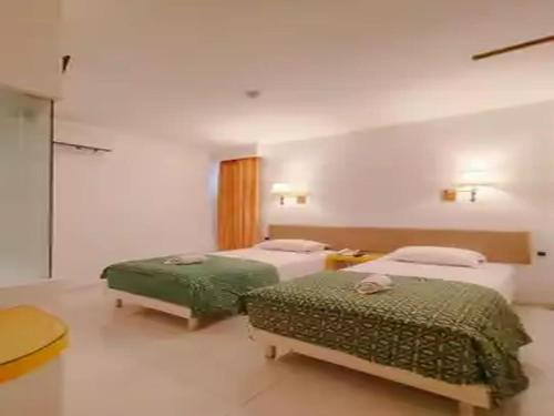 a bedroom with two beds with green sheets at Dewarna Hotel Arifin in Malang