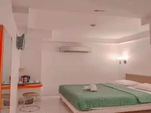 a white room with a green bed in it at Dewarna Hotel Arifin in Malang