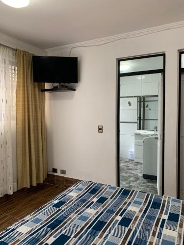 a bedroom with a bed and a tv on the wall at Apart Hotel Vicencio Iquique in Iquique