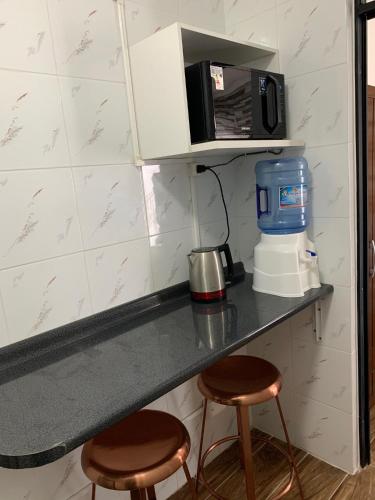 a kitchen counter with two stools and a microwave at Apart Hotel Vicencio Iquique in Iquique