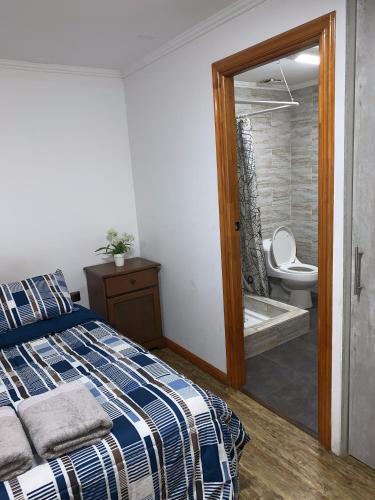 a bedroom with a bed and a bathroom with a toilet at Apart Hotel Vicencio Iquique in Iquique