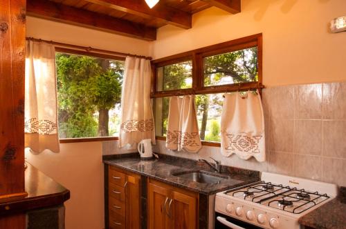 a kitchen with a sink and a stove and two windows at KaiKen Lauquen in Trevelin