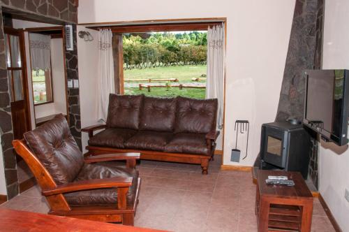 a living room with a leather couch and a tv at KaiKen Lauquen in Trevelin