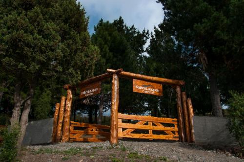 a wooden gate with signs on it in a park at KaiKen Lauquen in Trevelin