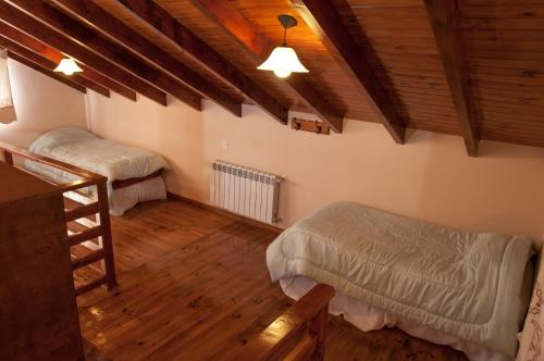 a bedroom with two beds and a wooden ceiling at KaiKen Lauquen in Trevelin