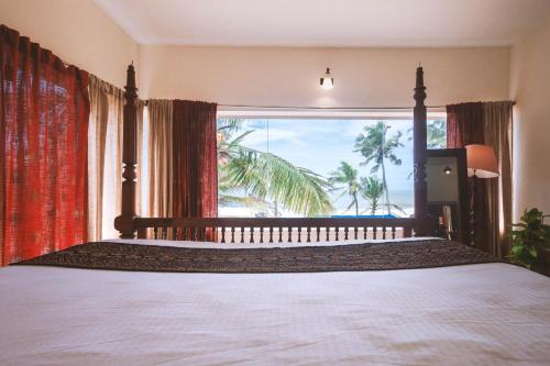 a bedroom with a bed and a large window at Santa Maria, Trivandrum - An Airport Boutique by the Sea in Trivandrum