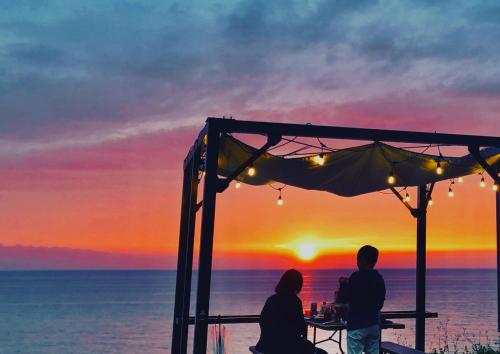 a couple sitting at a table watching the sunset at AWAJI OCEAN BASE west coast in Tusi