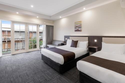 a hotel room with two beds and a couch at Quality Hotel Melbourne Airport in Melbourne