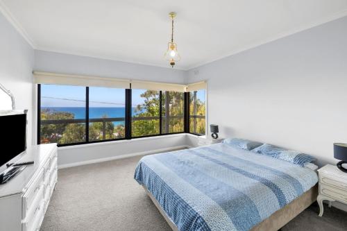 a bedroom with a bed and a large window at Retro Retreat in Lorne