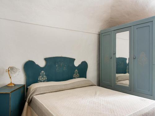 1 dormitorio con 1 cama con cabecero azul y espejo en Quaint holiday home in Calizzano in a nice area, en Calizzano