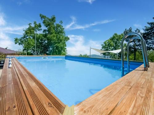 uma piscina com água azul e um deque de madeira em Belvilla by OYO Casale Verbena em Tavoleto