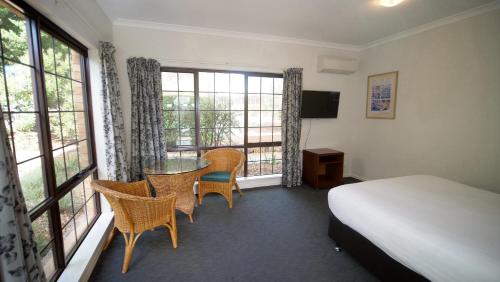 1 dormitorio con 1 cama, mesa y sillas en Margaret River Motel, en Margaret River Town