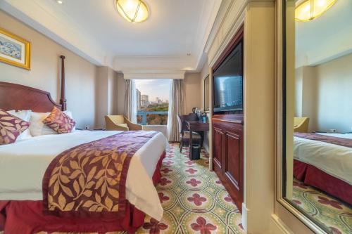 a hotel room with a bed and a flat screen tv at Ramada Yichang Hotel in Yichang