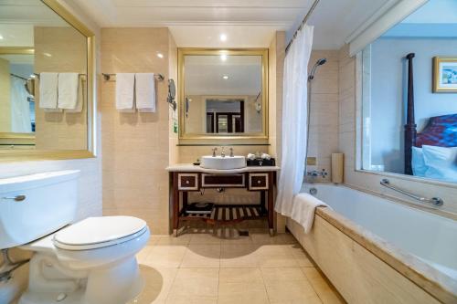 a bathroom with a toilet and a sink and a tub at Ramada Yichang Hotel in Yichang